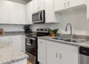 Thumbnail 2 of 42 - a kitchen with white cabinets and granite counter tops and a sink at The View on Collins, Lansing, MI, 48910
