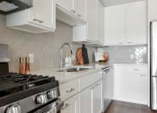 Thumbnail 3 of 57 - a white kitchen with stainless steel appliances and white cabinets