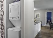 Thumbnail 11 of 30 - a white washer and dryer in a room next to a kitchen