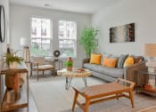 Thumbnail 7 of 42 - a living room with a gray couch and a large window at The View on Collins, Michigan, 48910