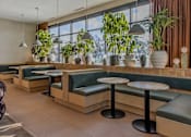 Thumbnail 38 of 83 - A restaurant with green plants and wooden tables.