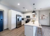 Thumbnail 46 of 79 - a kitchen with white cabinets and stainless steel appliances and a white counter top at The Commons at Rivertown, Grandville