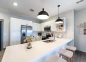 Thumbnail 47 of 79 - a kitchen with a white counter top and a stainless steel refrigerator at The Commons at Rivertown, Grandville, MI
