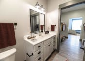 Thumbnail 58 of 79 - a bathroom with a sink and a mirror and a door to a bedroom at The Commons at Rivertown, MI