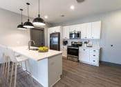 Thumbnail 73 of 79 - a kitchen with white cabinets and a large island with a white counter top at The Commons at Rivertown, MI