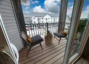 Thumbnail 36 of 79 - a porch with two chairs and a balcony with a view at The Commons at Rivertown, Grandville, Michigan