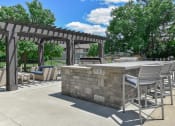 Thumbnail 21 of 30 - a patio with a stone bar and chairs and a pergola