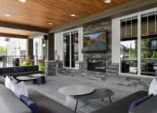 Thumbnail 20 of 79 - a covered patio with couches and tables and a fireplace at The Commons at Rivertown, Grandville, MI