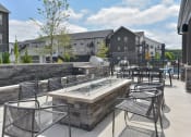 Thumbnail 21 of 79 - an outdoor patio with tables and chairs and a fire pit at The Commons at Rivertown, Grandville, MI, 49418