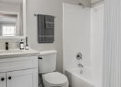 Thumbnail 15 of 43 - A white bathroom with a toilet, sink, and bathtub.