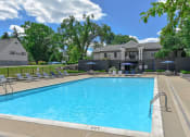 Thumbnail 15 of 30 - a swimming pool with chairs and a building in the background