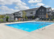 Thumbnail 11 of 79 - a swimming pool with an apartment building in the background at The Commons at Rivertown, Grandville, 49418