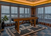 Thumbnail 64 of 83 - A large wooden table is in the middle of a room with a checkered rug.