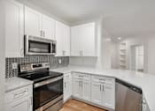 Thumbnail 5 of 19 - A kitchen with white cabinets and appliances.