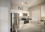 Thumbnail 2 of 19 - A kitchen with a refrigerator, microwave, oven, and sink.