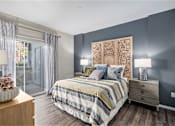 Thumbnail 6 of 19 - A bedroom with a bed, nightstand, and a large decorative wall panel.