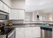 Thumbnail 2 of 19 - A kitchen with white cabinets and stainless steel appliances.