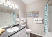 Thumbnail 10 of 19 - A bathroom with a sink, toilet, and a mirror.