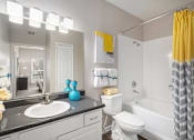 Thumbnail 9 of 19 - A bathroom with a white toilet, a sink, and a yellow shower curtain.