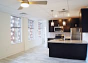 Thumbnail 1 of 5 - A kitchen with a black counter top and stainless steel appliances.