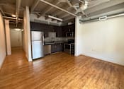 Thumbnail 6 of 10 - A kitchen with wooden floors and a refrigerator.