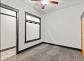 Thumbnail 16 of 21 - A room with a ceiling fan and carpeted floor.
