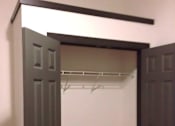 Thumbnail 8 of 9 - A white closet with a brown floor and two doors.