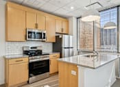 Thumbnail 2 of 9 - A kitchen with wooden cabinets and a granite countertop.