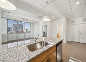 Thumbnail 3 of 9 - A kitchen with a granite countertop and stainless steel appliances.