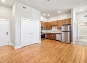 Thumbnail 2 of 9 - an empty kitchen with wood flooring and a stainless steel refrigerator