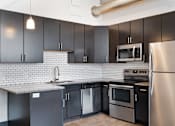 Thumbnail 7 of 13 - A kitchen with black cabinets and stainless steel appliances.