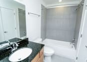 Thumbnail 2 of 21 - A bathroom with a black granite countertop and white fixtures.