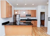 Thumbnail 17 of 21 - A kitchen with wooden cabinets and black countertops.
