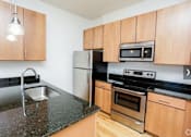 Thumbnail 15 of 21 - A kitchen with wooden cabinets and black countertops.