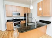 Thumbnail 7 of 21 - A kitchen with wooden cabinets and a granite countertop.