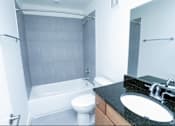 Thumbnail 9 of 21 - A white toilet sits next to a white bathtub in a bathroom.