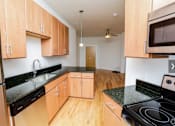 Thumbnail 18 of 21 - A kitchen with wooden cabinets and black countertops.