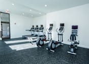 Thumbnail 5 of 21 - A gym with a row of exercise bikes and a door marked exit.