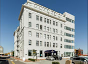 Thumbnail 19 of 21 - A white building with a black car parked in front.