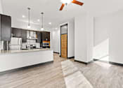 Thumbnail 3 of 21 - A modern kitchen with a wooden floor and white walls.