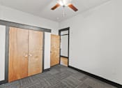 Thumbnail 12 of 21 - A room with a ceiling fan and a row of wooden doors.