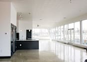 Thumbnail 6 of 8 - A kitchen with black cabinets and a large island with a sink.