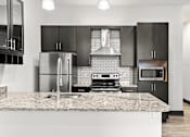 Thumbnail 4 of 21 - A modern kitchen with a granite countertop and stainless steel appliances.