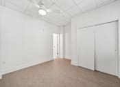 Thumbnail 6 of 9 - A white room with a ceiling fan and carpeted floor.