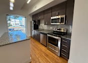 Thumbnail 2 of 10 - A modern kitchen with stainless steel appliances and wooden floors.