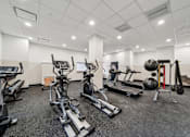 Thumbnail 9 of 9 - A spacious gym with a variety of equipment including treadmills, stationary bikes, and weight machines.