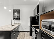 Thumbnail 8 of 21 - A modern kitchen with black cabinets and stainless steel appliances.