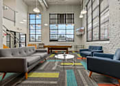Thumbnail 3 of 17 - A modern living room with a grey sofa, blue armchair, and a coffee table.