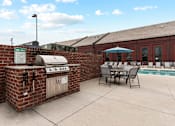 Thumbnail 6 of 17 - A patio with a grill and chairs is set up outside.