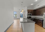 Thumbnail 14 of 17 - A kitchen with a granite countertop and stainless steel appliances.
